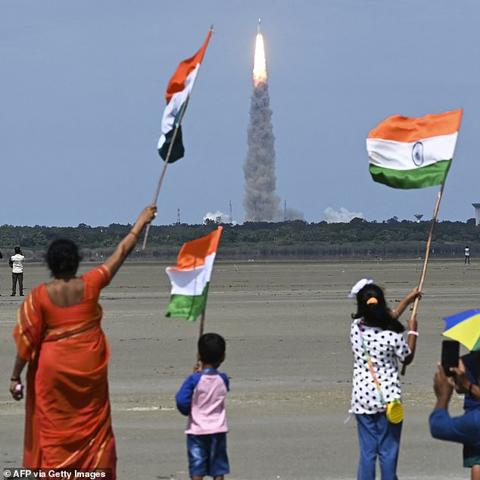 Locals wave the Indian flag as an Indian Space Research Organisation (ISRO) rocket carrying the Chandrayaan-3 spacecraft lifts off from the Satish Dhawan Space Centre in Sriharikota, an island off the coast of southern Andhra Pradesh state on July 14, 2023