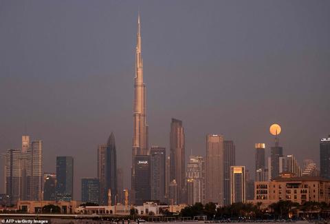 UNITED ARAB EMIRATES: The Blue Moon rises behind the world s tallest building, the Burj Khalifa, and the Dubai skyline