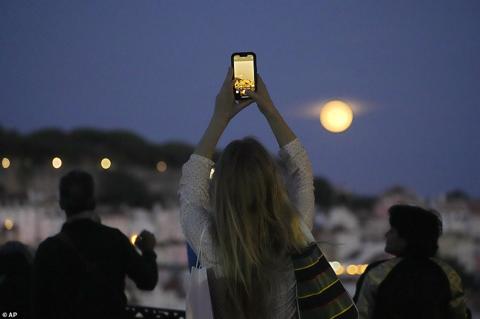 LISBON: A woman takes pictures of a supermoon rising above Lisbon