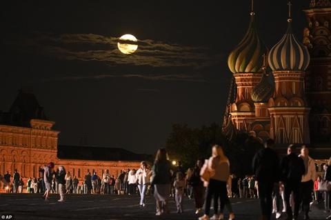 RUSSIA: The August Super Blue Moon sets behind a historical building and the St. Basil s Cathedral, right, as people walk in Red Square in Moscow