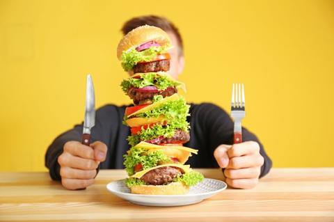Man eating huge burger at table