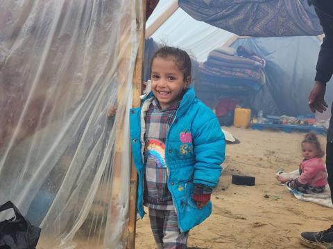 طفلة فلسطينية نازحة تبتسم أمام خيمة تقيم بها مع أسرتها في منطقة المواصي الأقرب على الحدود الفلسطينية المصرية جنوب قطاع غزة.