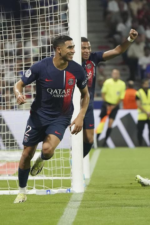 PSG s Achraf Hakimi, left, celebrates with Kylian Mbappe after scoring his side s second goal during the French League One soccer match between Lyon and Paris Saint-Germain at the Groupama stadium, outside Lyon, France, Sunday, Sept. 3, 2023. (AP Photo/Laurent Cipriani)